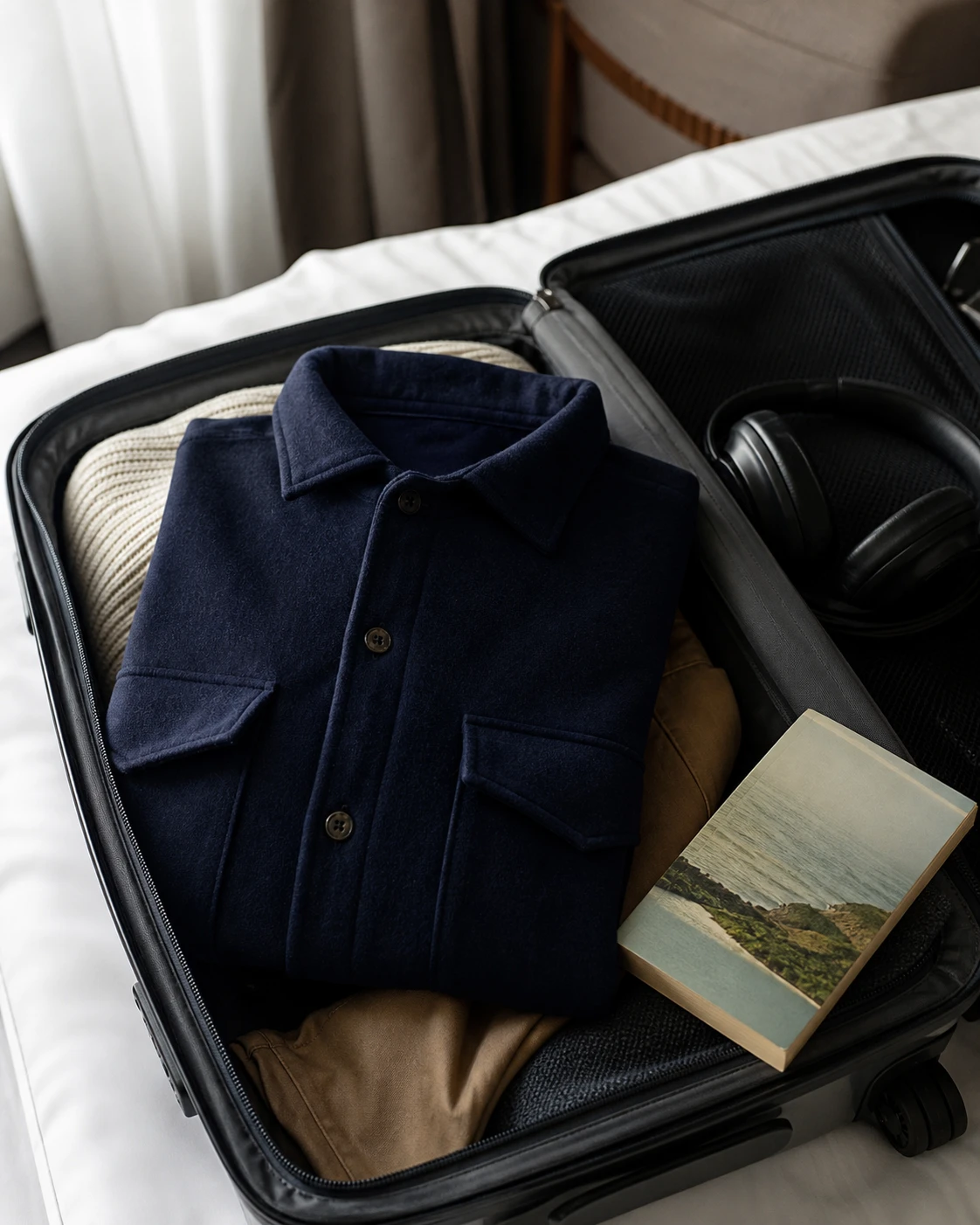 A navy overshirt packed in an open carry-on suitcase