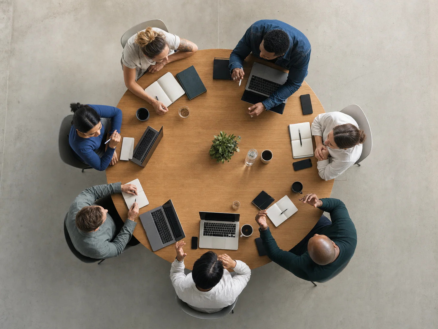 Editorial scene viewed directly overhead of founders working and networking around a circular table