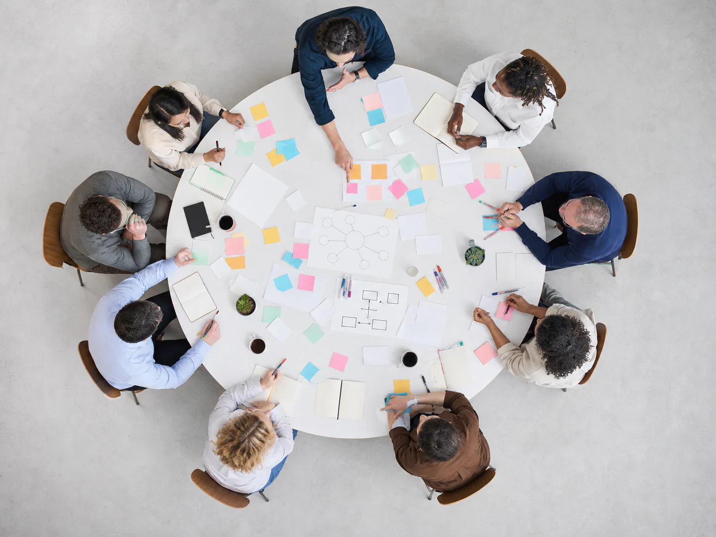 Editorial scene viewed directly overhead of operators collaborating in a workshop around a circular table